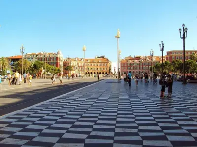 a city street with people walking on a sidewalk at PALAIS OTHELLO in Nice