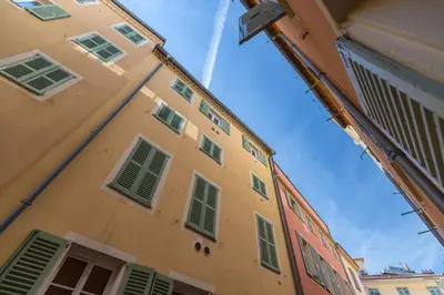 a tall yellow building with green shuttered windows at Studio en plein cœur de la vieille ville à Nice in Nice
