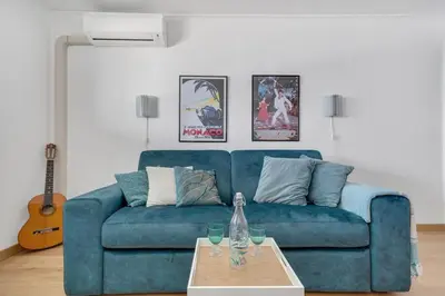 a blue couch in a living room with a table at La Prom - a two bedroom apartment with a sea view in Nice