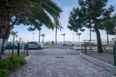 a parking lot with parked cars and palm trees at La Prom - a two bedroom apartment with a sea view in Nice