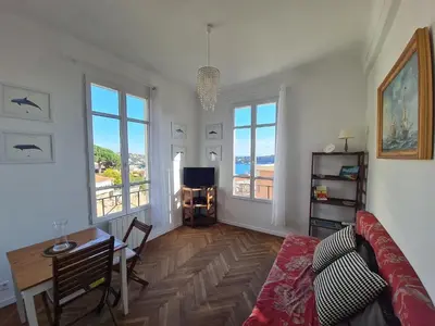 a living room with a couch and a table and windows at Les Lauriers in Villefranche-sur-Mer