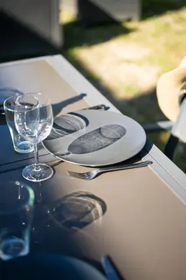 a table with plates and wine glasses on it at Cosy & Chill Appartements - 10 min de la mer - Jardin, Netflix, terrasse, fibre & parking in Cagnes-sur-Mer