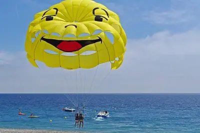 a large yellow kite with a face on it on the beach at Bienvenue sur la Cote d'Azur in Nice
