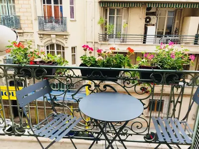 a table and chairs on a balcony with flowers at Le GIULIANO in Nice