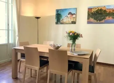 a dining room table with chairs and a vase of flowers at Le GIULIANO in Nice