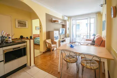 a kitchen and living room with a table and chairs at Joli 2 pièces climatisé à 150m de la plage in Nice