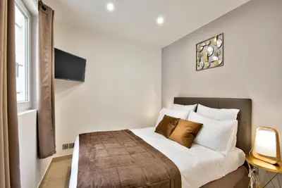 a bedroom with a bed with white pillows and a television at Home Inn - Centre ville - Nice in Nice