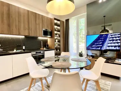 a kitchen with a glass table and white chairs at Maxim - Easy Home Booking in Nice