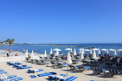 a beach with chairs and umbrellas and the ocean at Azur 3000 in Saint-Laurent-du-Var
