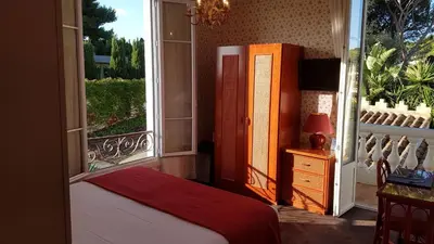 a bedroom with a bed and a large window at Hôtel de Charme Brise Marine in Saint-Jean-Cap-Ferrat