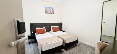 a hotel room with a bed and a tv at Evelia Hotels in Nice