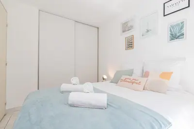 a white bedroom with a bed with two towels on it at Comfortable 1 Bdr Downtown - AC & Parking in Nice