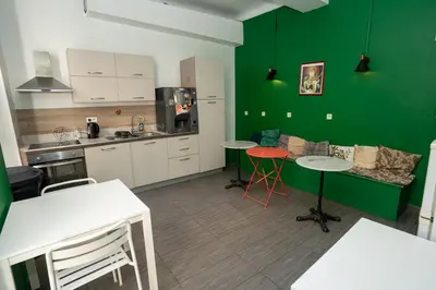 a kitchen with green walls and tables and chairs at Le Pastoral in Nice