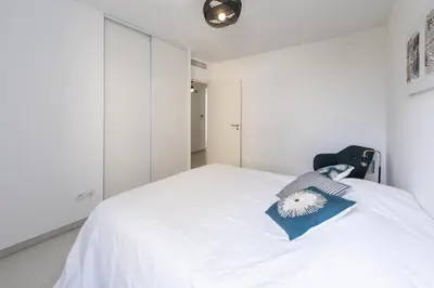 a bedroom with a white bed and a white wall at Elegance in Nice