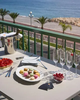 a table with a plate of food and wine glasses at Sunlight Properties - Sky blue - 3 bedroom flat with sea view on the Promenade des Anglais in Nice