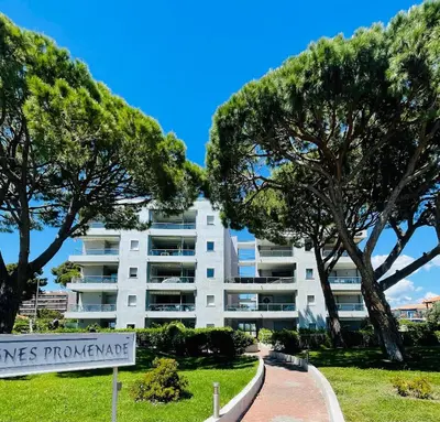 a white apartment building with trees in front of it at Cocon douillet face à la mer de Cagnes sur mer in Cagnes-sur-Mer
