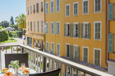 a table on a balcony in front of a building at SUEDE AP4207 by Riviera Holiday Homes in Nice