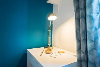 a table with a lamp on a blue wall at Cosy and Trendy 3 Bedrooms train tramway in Nice