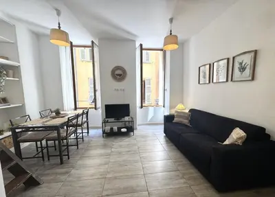 a living room with a black couch and a table at ApartHotel Riviera - Barillerie 12 - Vieille Ville 1mn plage - Appartement 2 pieces AC in Nice