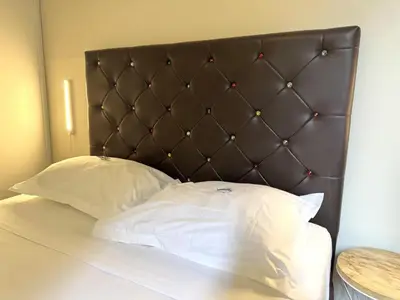 a bed with a brown headboard and two white pillows at ApartHotel Riviera - VINCENT 1 - Vieille Ville - Appartement Supérieur 2 pieces AC in Nice