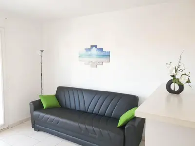 a black couch with green pillows in a room at Résidence Les domes, Piscine in Nice