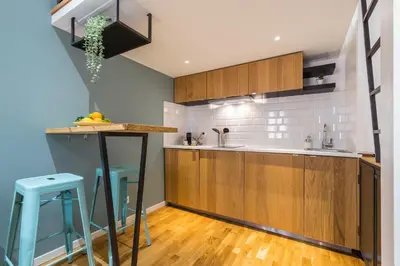 a kitchen with wooden cabinets and blue stools at 1 GALLO LOT 2 - Studio Mezzanine en plein coeur du vieux Nice in Nice