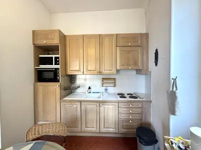 a small kitchen with wooden cabinets and a sink at ApartHotel Riviera - BALCON HONORE 1 - Old Town - 5 mn Promenade des Anglais et Plage - Charme Absolu - Appartement 2 pièces avec Balcon AC - Vue mer et Ville in Nice