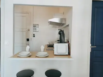 a small kitchen with a table with plates and a microwave at Joli Studio - Promenade des Anglais - Accès plage in Nice