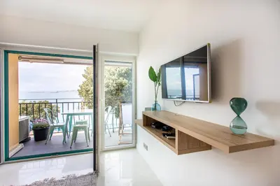 a living room with a television and a balcony at I love Nice - FACE MER, DESIGN, TERRASSE, ASC, WIFI, CLIM in Nice