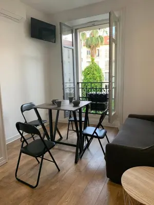 a living room with a table and chairs and a couch at Nice Centre: à 300m de la mer et de la Promenade des Anglais in Nice
