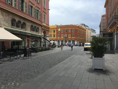 a cobblestone street in a city with buildings at Palais Gioffredo place Massena in Nice