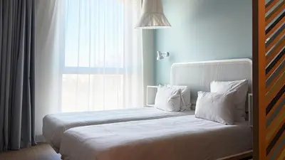 a bedroom with a bed with white pillows and a window at OKKO Hotels Nice Aéroport in Nice