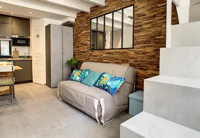 a living room with a couch and a brick wall at Nestor&Jeeves - SECRET BEACH DUPLEX - Very close sea - Atypical in Nice