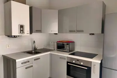 a white kitchen with a microwave and a sink at Grand Studio avec Coin Nuit et Parking in Saint-Laurent-du-Var