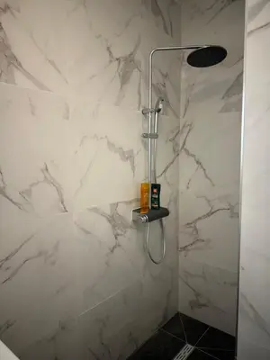 a shower in a bathroom with white marble walls at Grand Studio avec Coin Nuit et Parking in Saint-Laurent-du-Var