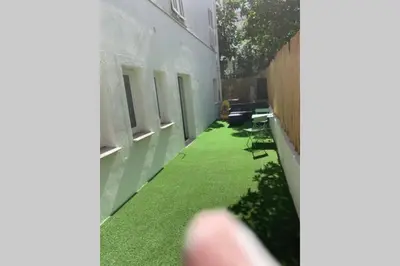 a small yard with green grass on the side of a building at Appartement neuf 4-6 personnes en bord de Mer in Nice