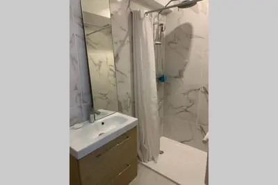 a bathroom with a sink and a shower with a mirror at Appartement neuf 4-6 personnes en bord de Mer in Nice