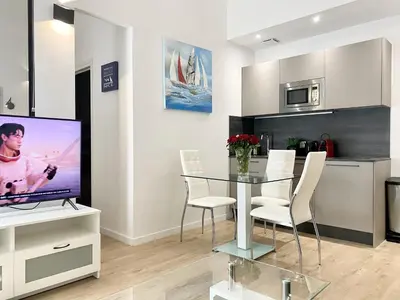 a dining room with a glass table and a tv at Central Modern Flat Lamartine in Nice