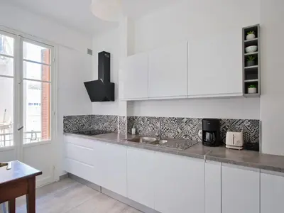a white kitchen with white cabinets and a sink at Le Philanthrope - Balcon Wifi Climatisation in Nice