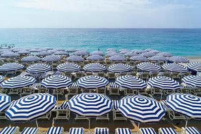 a bunch of blue and white umbrellas on a beach at Studio neuf 25 m2, terrasse 35 m2 proche port Nice, Centre ville in Nice