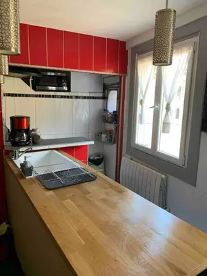 a kitchen with red cabinets and a wooden counter top at Cosy sweet space in paradise - 5min from the beach in Nice