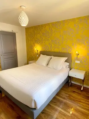 a bedroom with a large white bed with yellow wallpaper at Maison de la Marine in Cagnes-sur-Mer