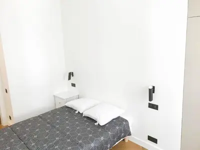 a bedroom with a bed and a white wall at Buffa Résidence in Nice