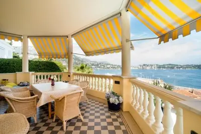 a balcony with a table and chairs and the ocean at La NONETE in Villefranche-sur-Mer