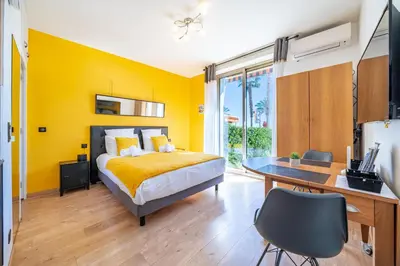 a bedroom with yellow walls and a desk and a bed at Studio de la plage - Mer, Terrasse et garage in Cagnes-sur-Mer