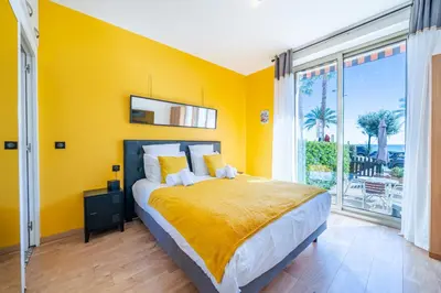 a yellow bedroom with a bed and a large window at Studio de la plage - Mer, Terrasse et garage in Cagnes-sur-Mer