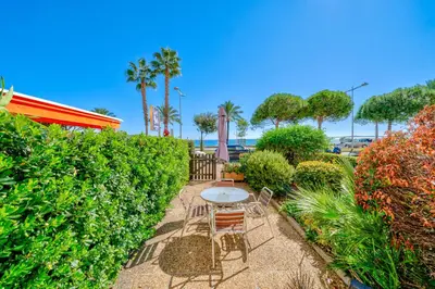 a patio with a table and chairs and bushes at Studio de la plage - Mer, Terrasse et garage in Cagnes-sur-Mer