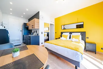 a yellow bedroom with a bed and a table at Studio de la plage - Mer, Terrasse et garage in Cagnes-sur-Mer
