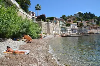 a woman laying on a beach next to a body of water at 3 Piéces confort climatisé vue mer, 4 personnes à Saint-Jean Cap Ferrat à proximité de monaco et menton in Saint-Jean-Cap-Ferrat