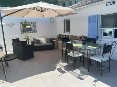 a patio with a table and chairs and an umbrella at Maisonnette Cagnes in Cagnes-sur-Mer